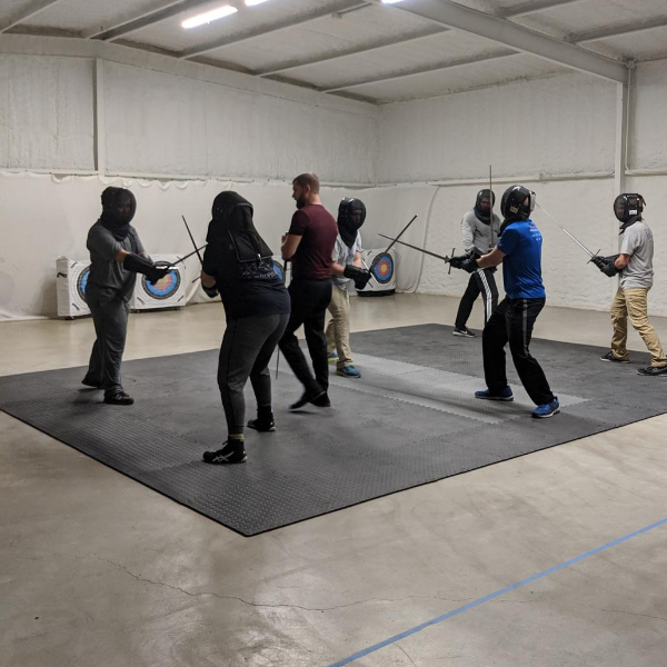 Beginner fight training, instructor leads a group of students with longswords.